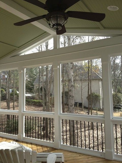 a screened porch with chairs and a ceiling fan