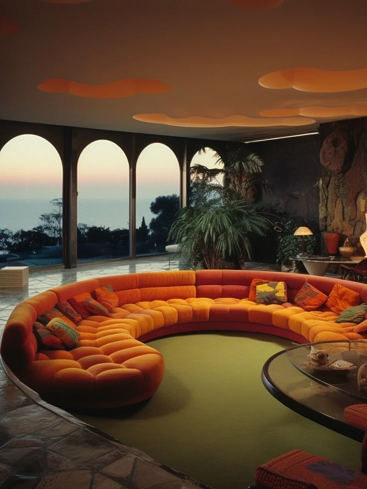 an orange couch sitting in the middle of a living room next to a large window