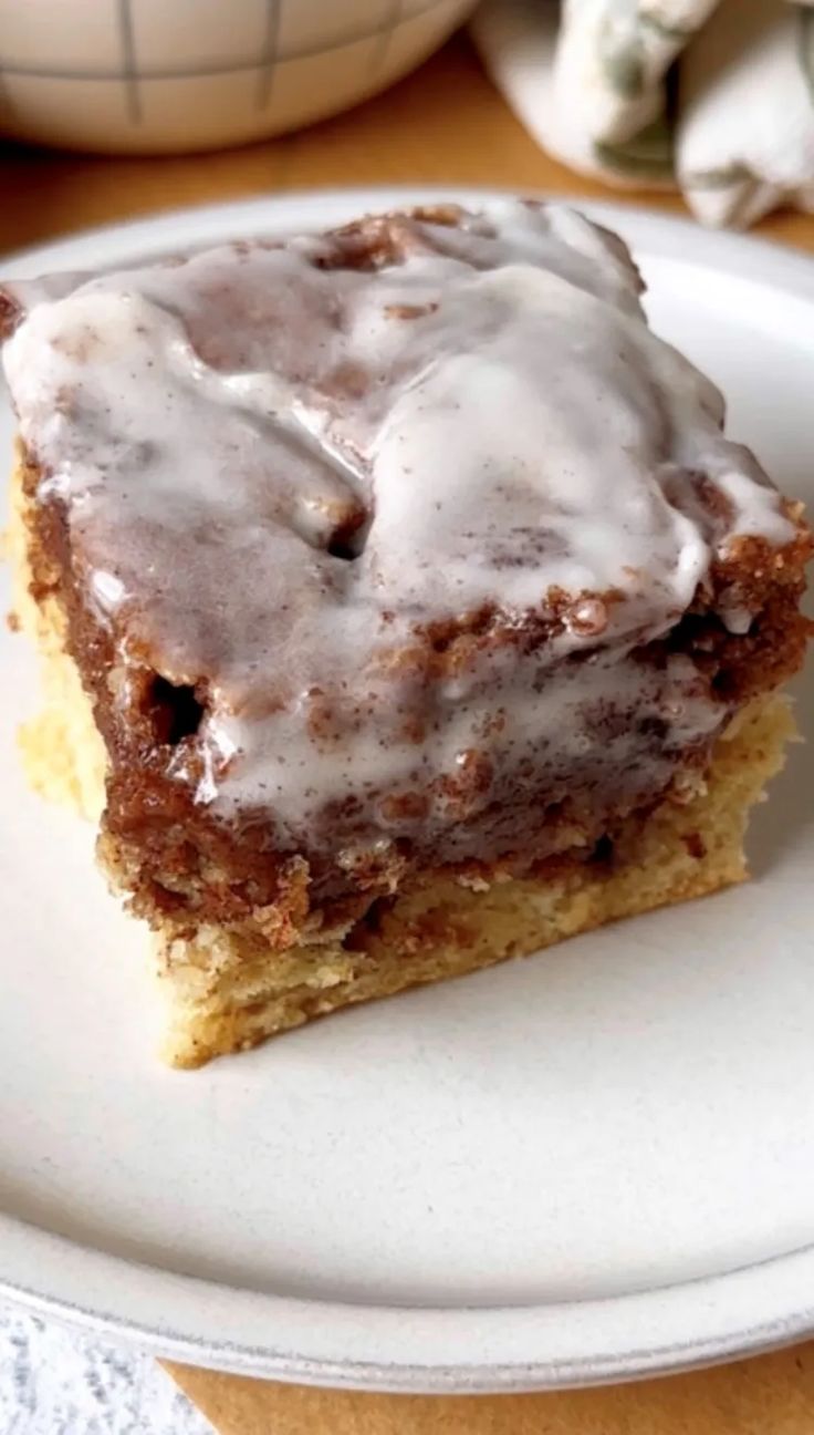 a white plate topped with a piece of cake covered in frosting