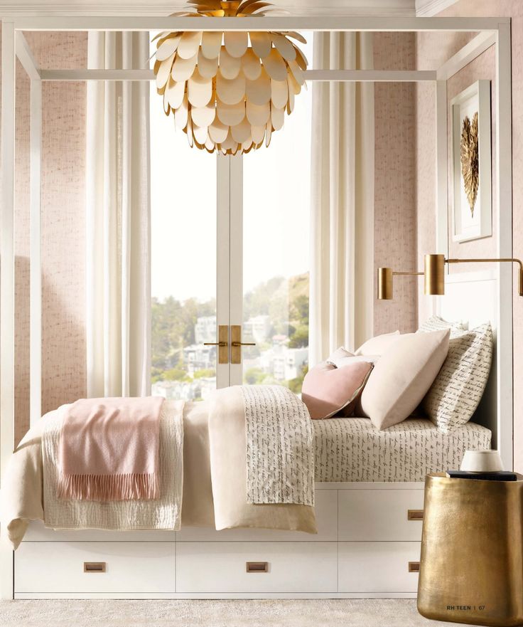 a bedroom with pink and white decor, gold accents and a chandelier hanging from the ceiling