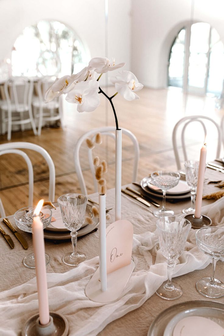 the table is set with white flowers and place settings