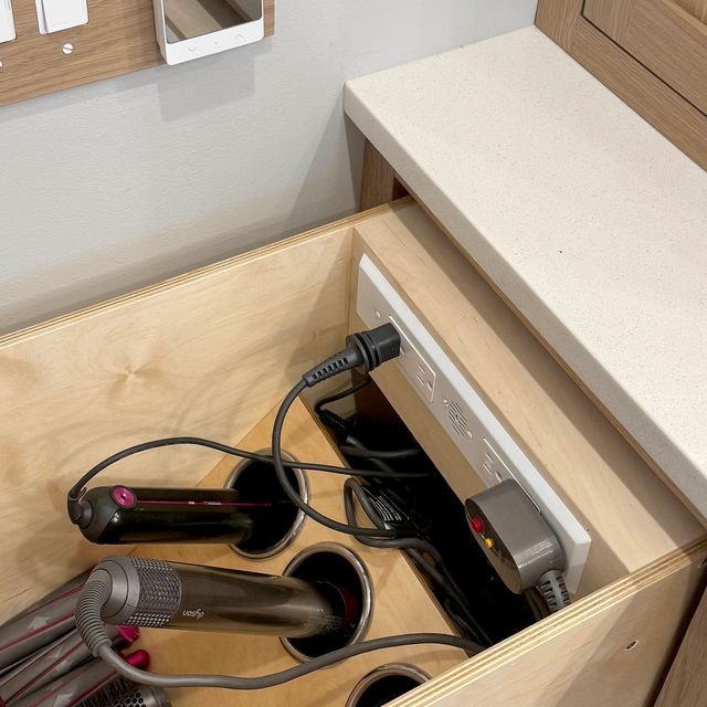 an open drawer with hair dryers and other items in it on the counter top