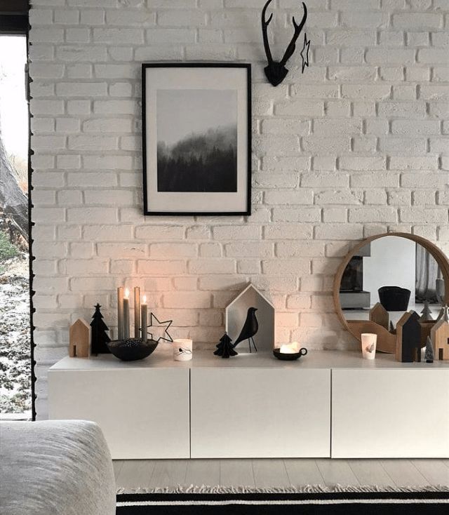 a white brick wall with candles and pictures on the top shelf in front of it