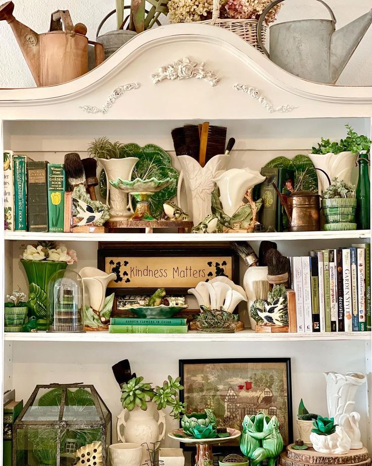 a white bookcase filled with lots of green plants and potted plants on top of it