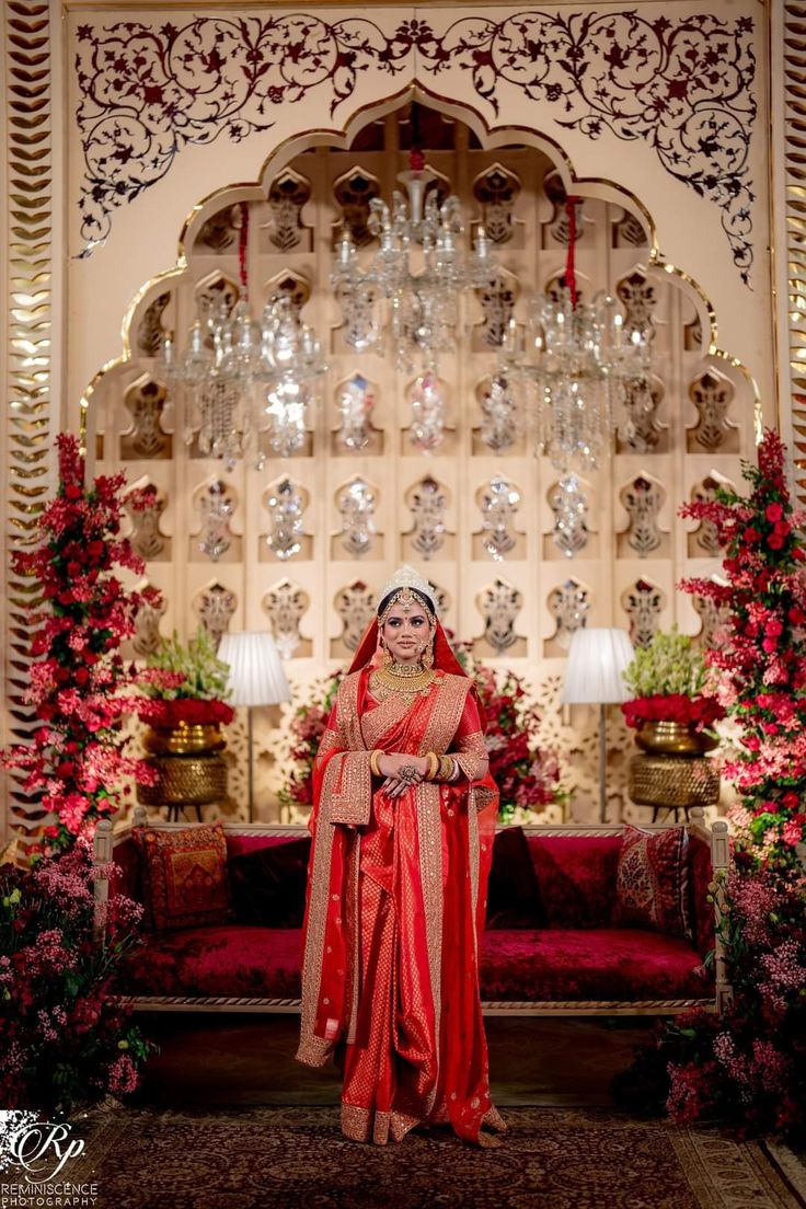 a woman in a red and gold outfit standing in front of a chandelier