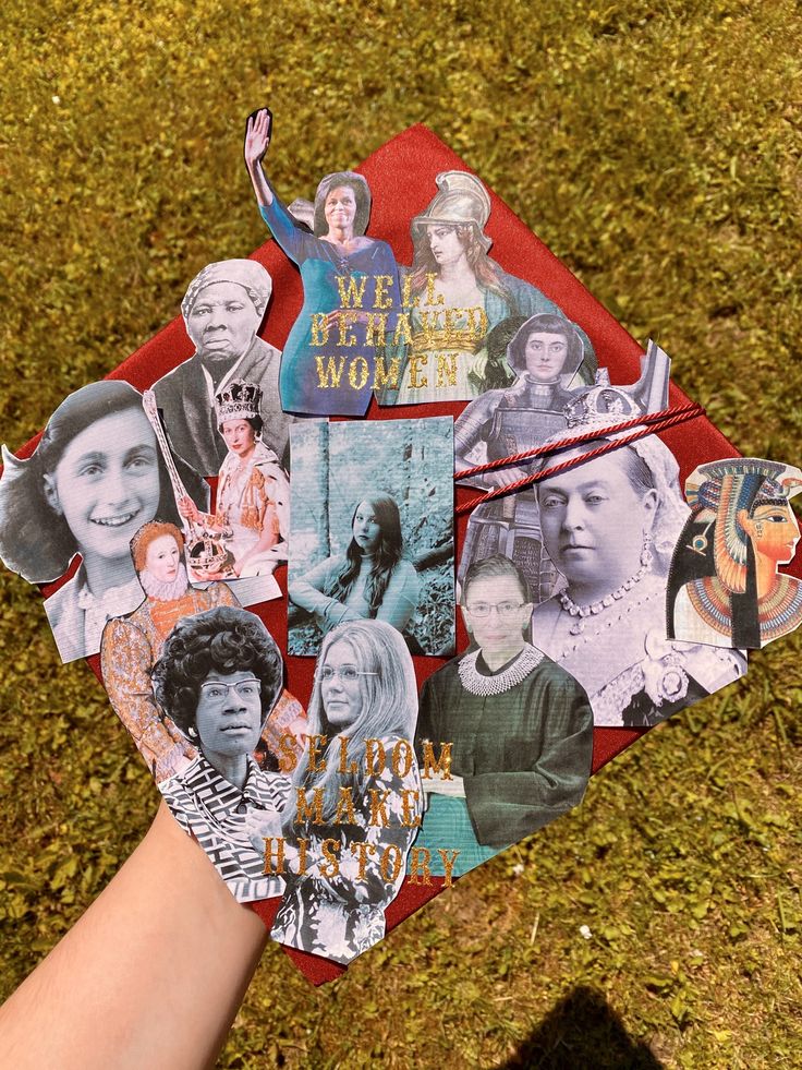 a person's hand is holding a kite with pictures of women on it in the grass