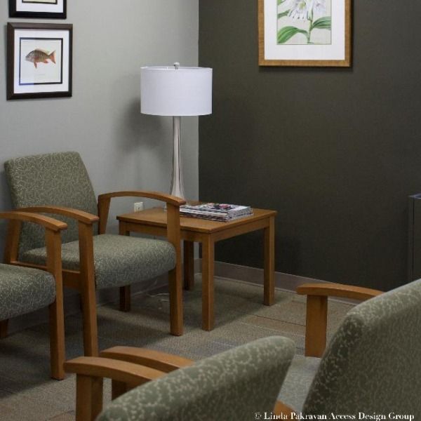 two chairs and a table in a room with framed pictures on the wall behind them