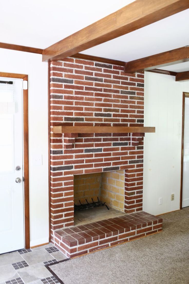 an empty living room with a brick fireplace and tile floor in front of the door