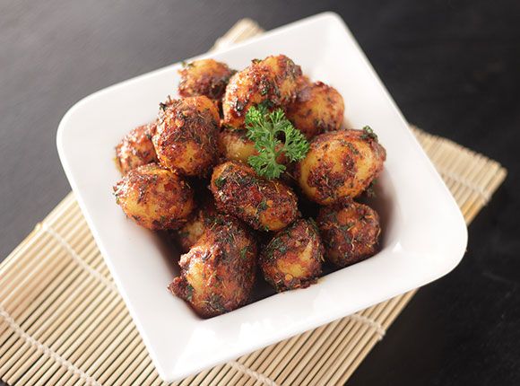 a white bowl filled with fried food on top of a bamboo place mat next to a black table