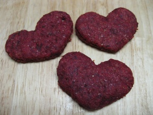 three heart shaped cookies sitting on top of a wooden table