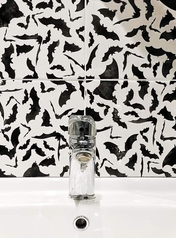 a bathroom sink with a glass faucet and black and white tile behind it