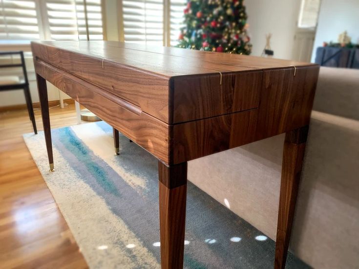 a wooden table sitting on top of a hard wood floor next to a christmas tree