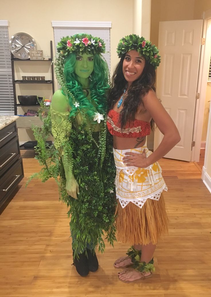 two women dressed in hula skirt and grass skirts standing next to each other on a hard wood floor