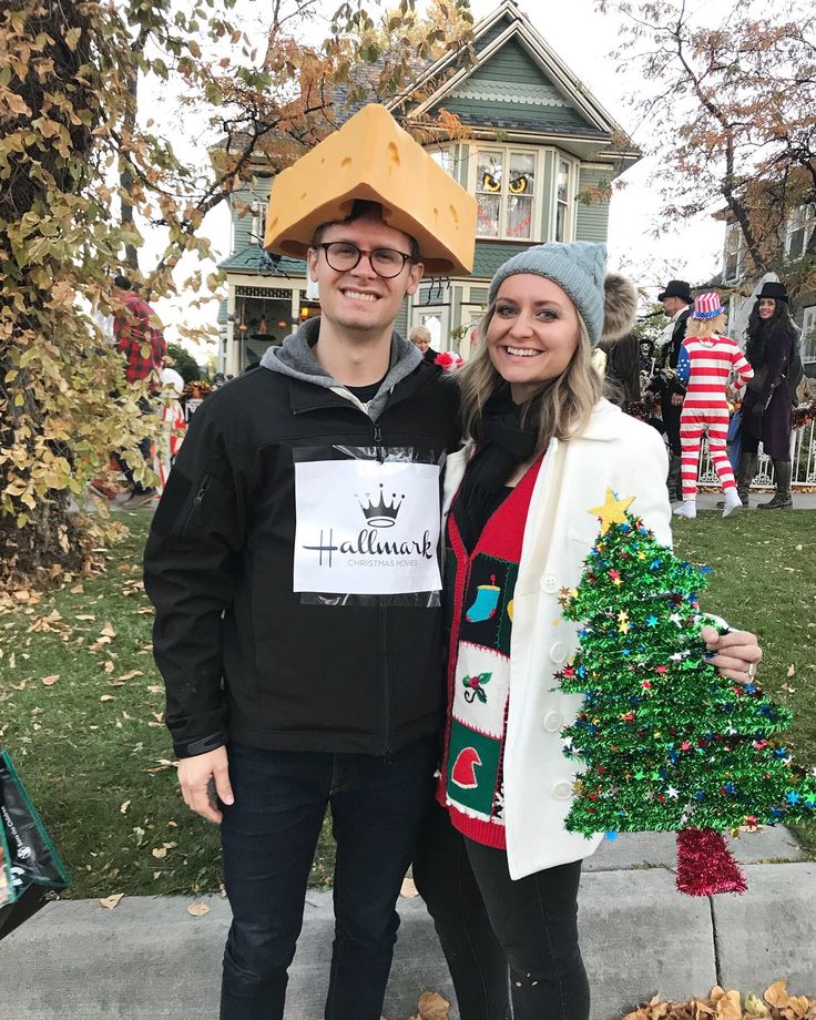 a man and woman standing next to each other in front of a house decorated for christmas