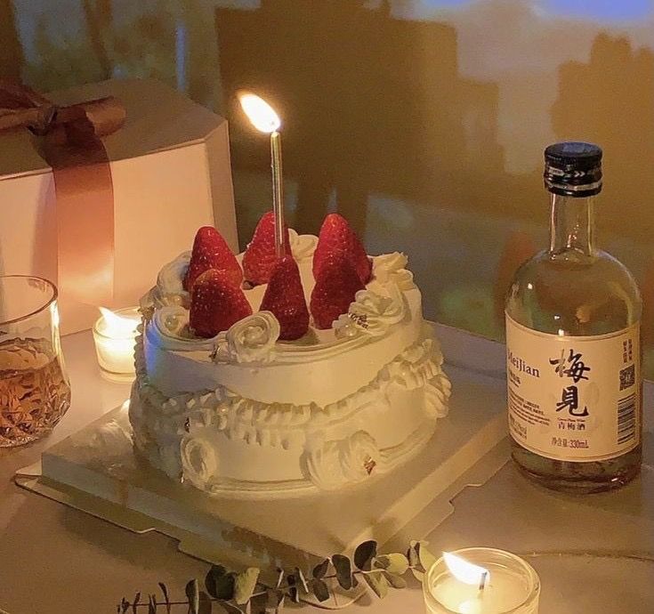 a white cake with strawberries on top and two candles in the middle next to it