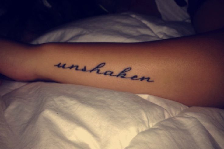 a person laying in bed with a tattoo on their arm that reads unshaken