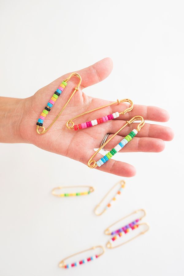 a person's hand holding several colorful pins and clips in different colors, all on their fingers