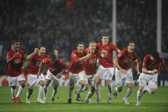 a group of men running on top of a field during a soccer game in the rain