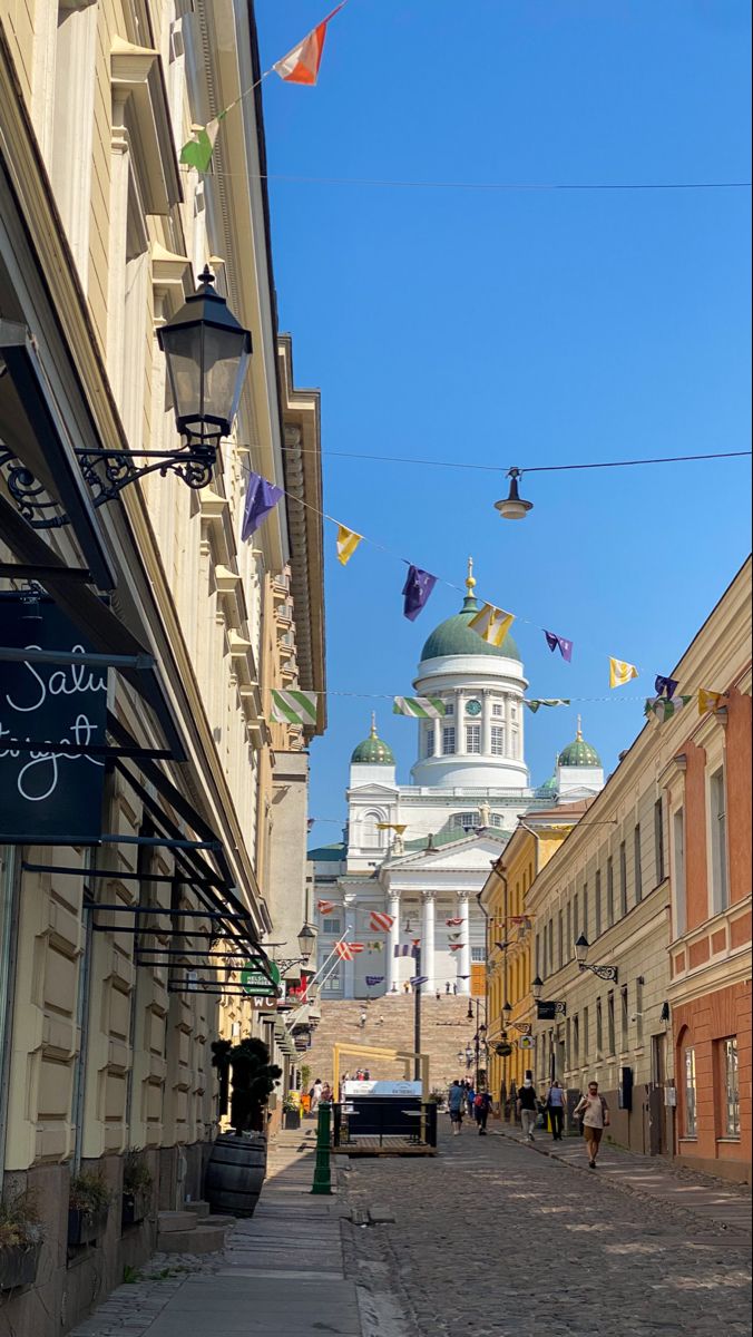 an old city street with buildings on both sides and flags flying in the air above