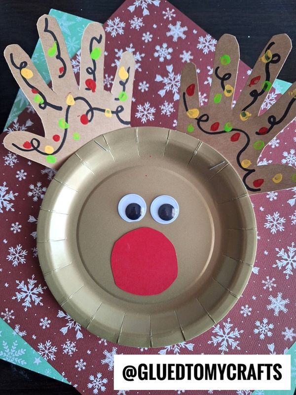 a paper plate with a reindeer face and handprinted christmas decorations on the side