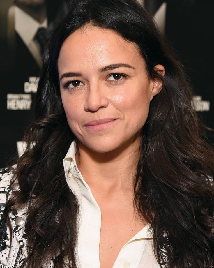 a close up of a person wearing a white shirt and long black hair, smiling at the camera