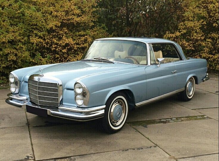 an old blue car is parked in front of some bushes