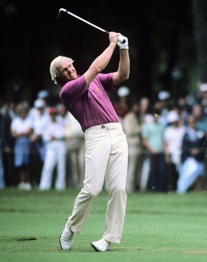 a man swinging a golf club on top of a green field with spectators in the background