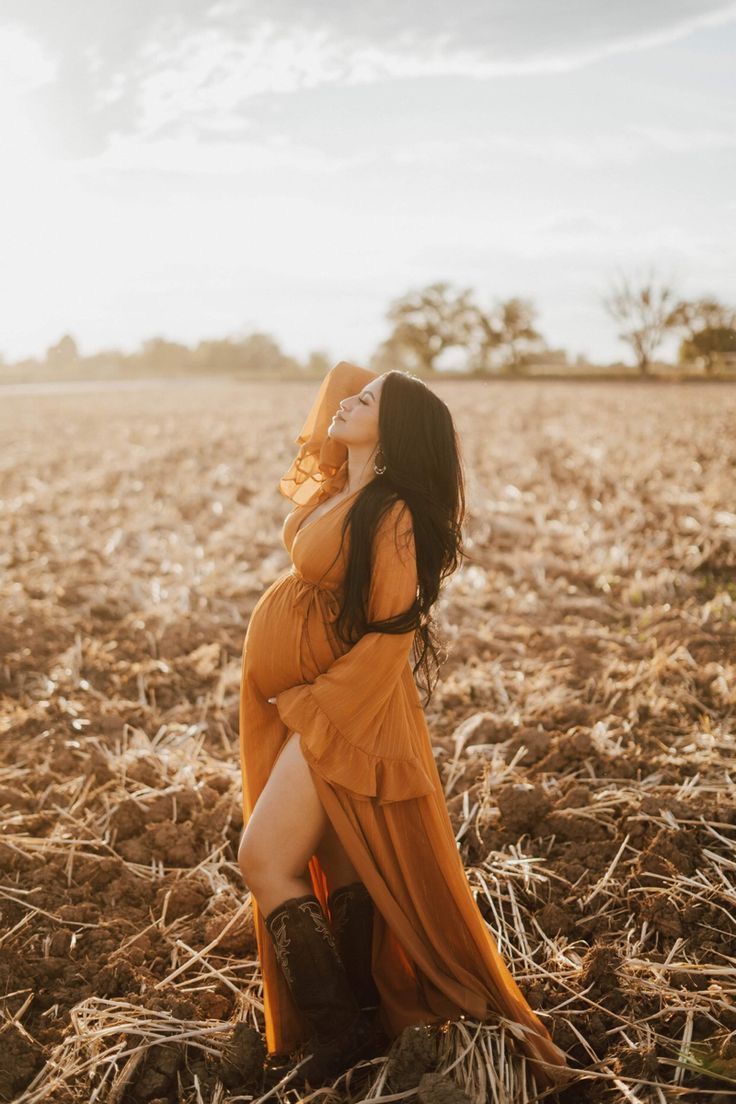 a woman in an orange dress standing in a field