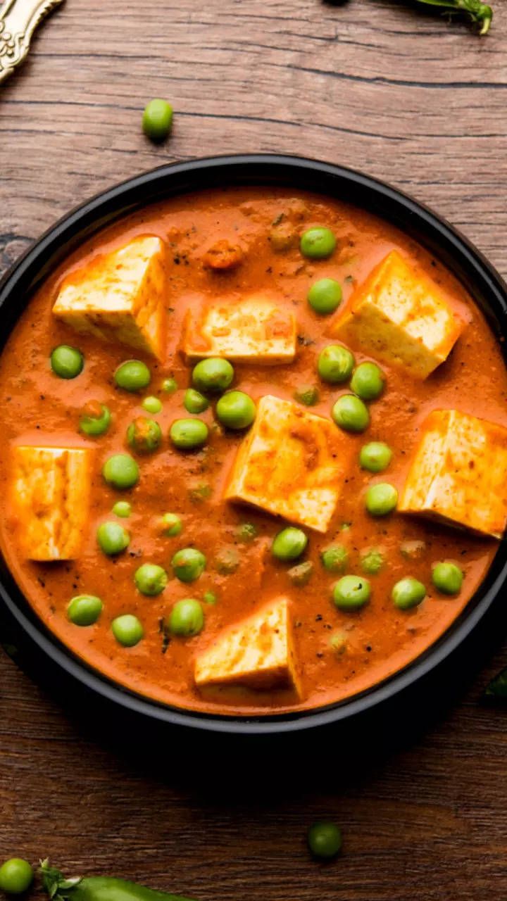 a black bowl filled with tofu and peas