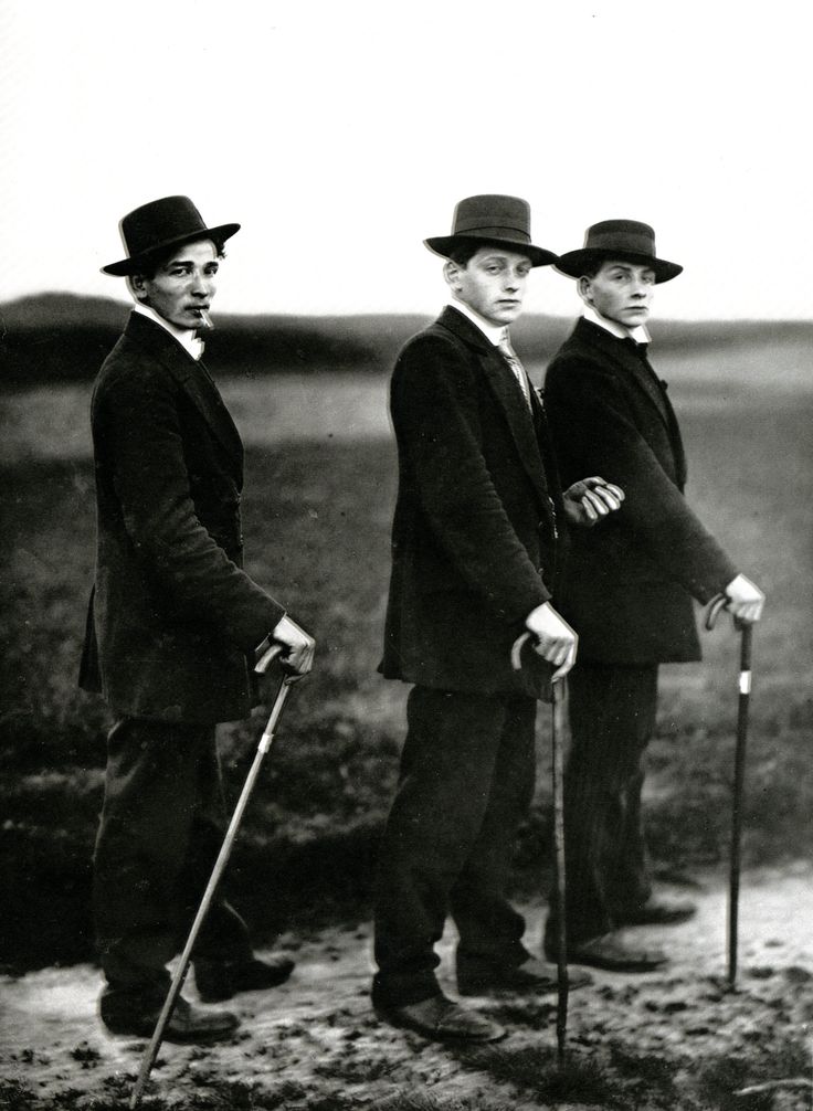 three men in suits and hats standing next to each other with canes on their heads