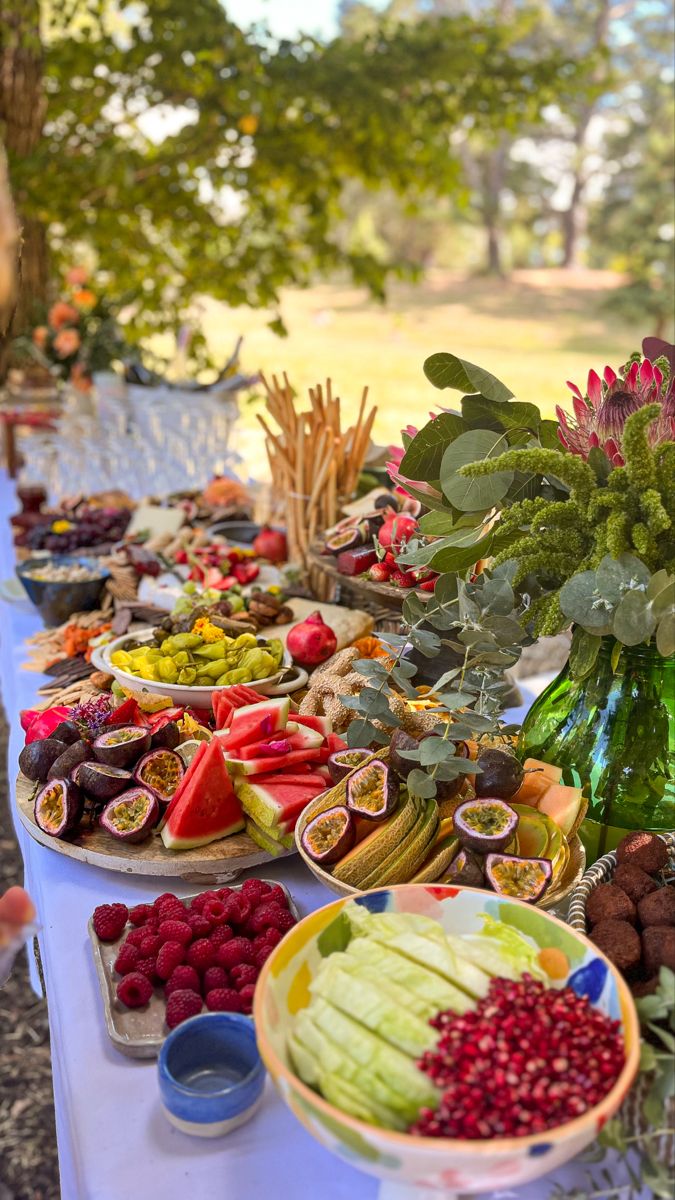 a table full of fruits and vegetables on it's side, with flowers in the background