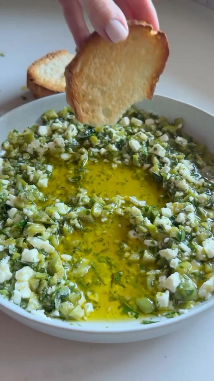 someone dipping some bread into a bowl of food