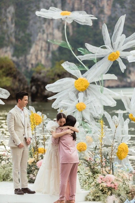 two people standing next to each other in front of flowers