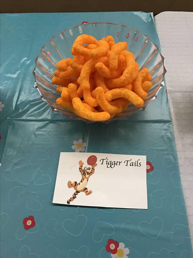 a glass bowl filled with cheetos sitting on top of a blue table cloth