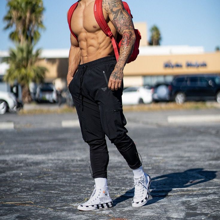 a shirtless man with tattoos standing in a parking lot