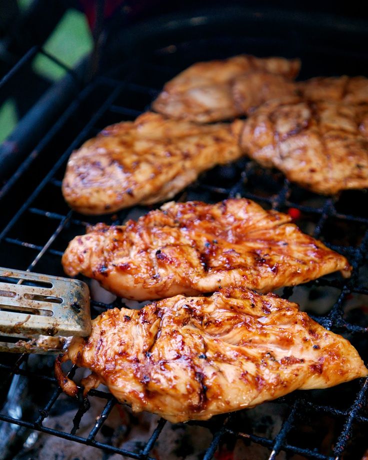 some chicken is cooking on the grill with a spatula