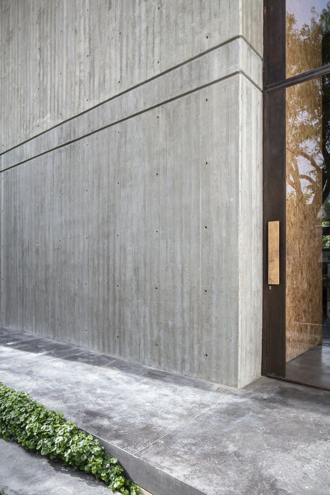 an entrance to a building with grass growing on the sidewalk