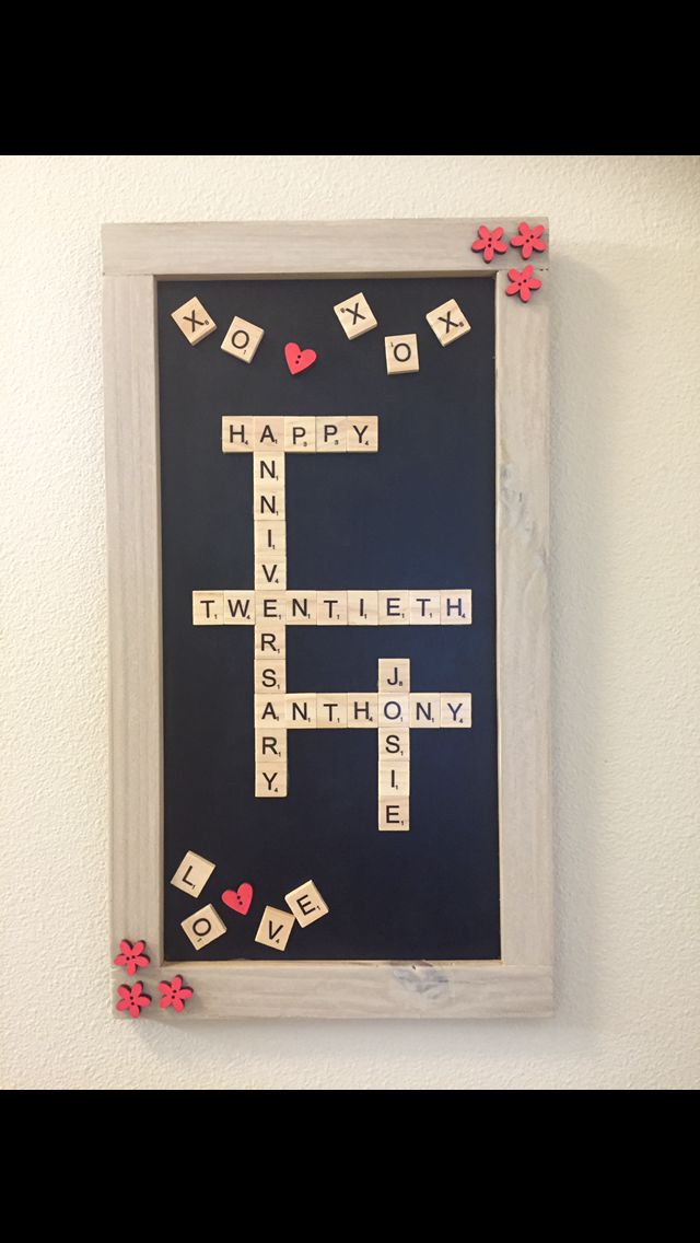 a cross made out of scrabble tiles hanging on the wall with hearts around it