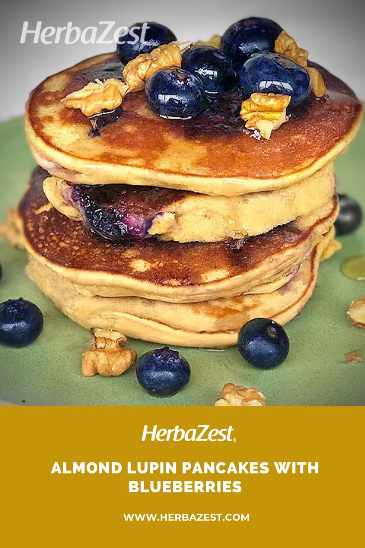 blueberry pancakes with almonds and syrup on a green plate, with text overlay