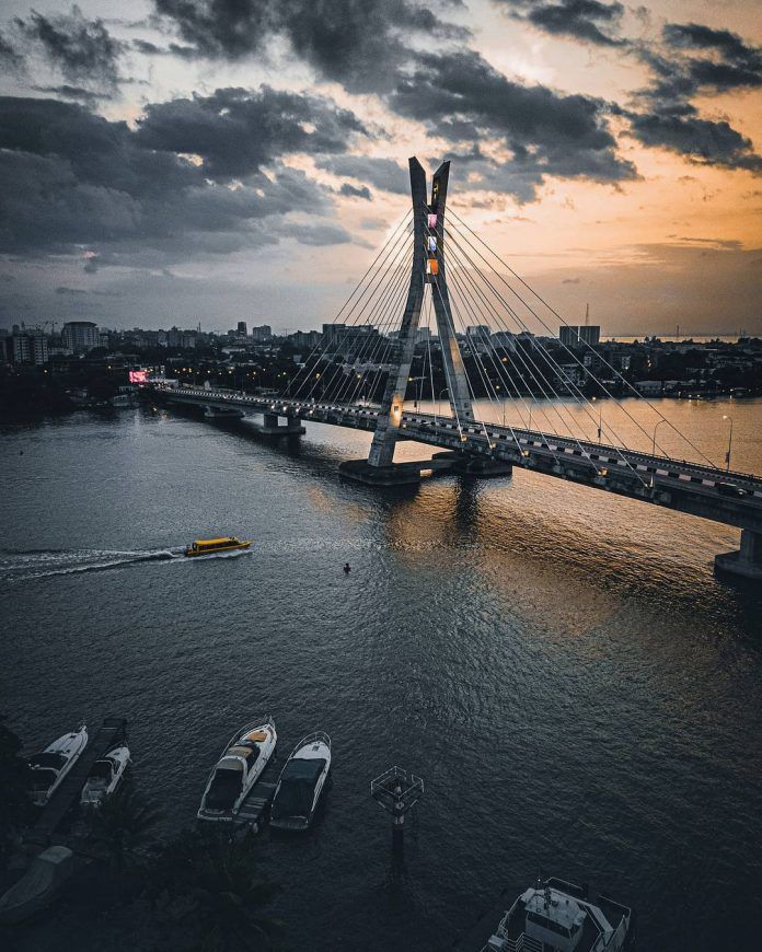 a bridge that is over some water with boats in the water and clouds above it