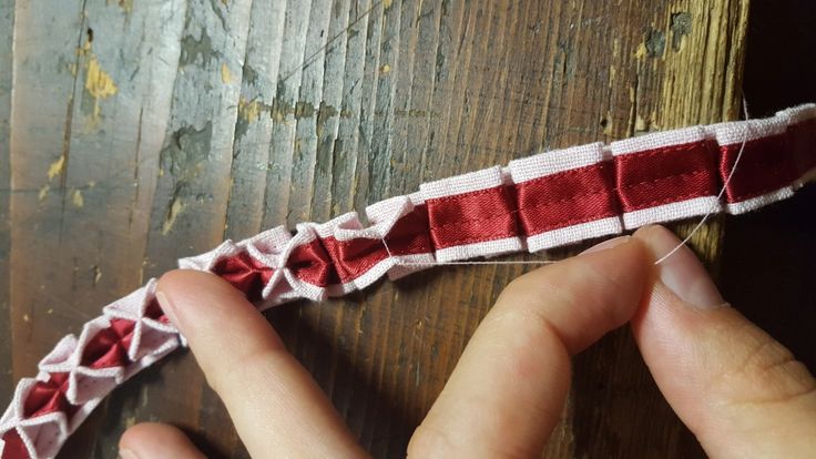 someone is sewing something with red and white ribbon