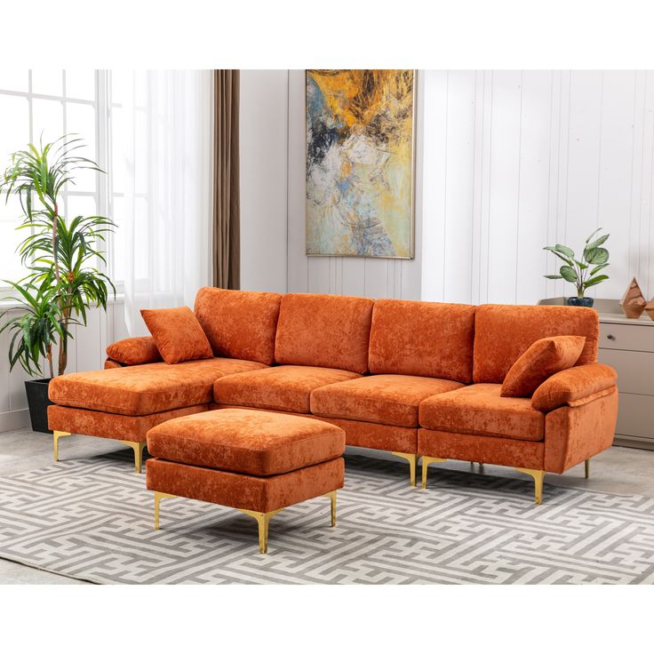 an orange sectional sofa with gold legs in a white living room filled with potted plants