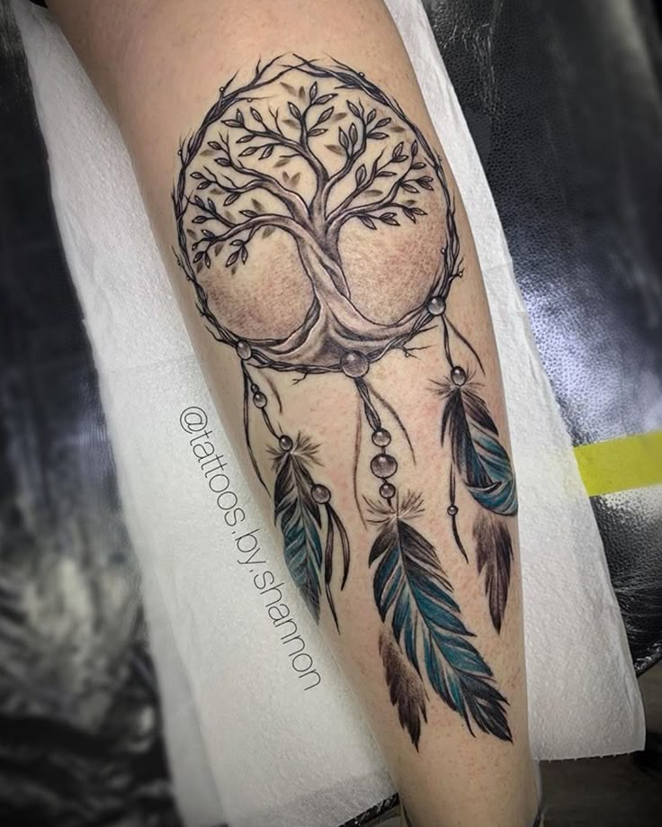 a person with a tattoo on their arm and leg, has a tree in the shape of a dream catcher