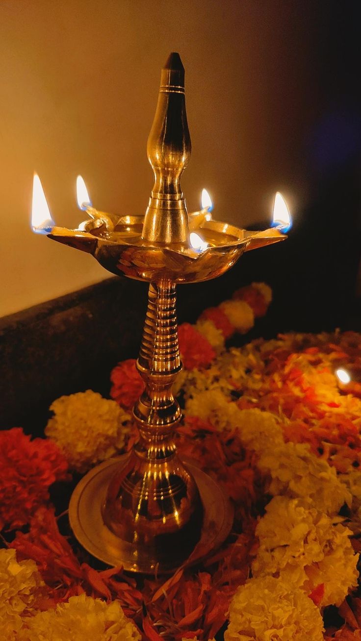 a metal candle holder sitting on top of a table filled with flowers and lit candles