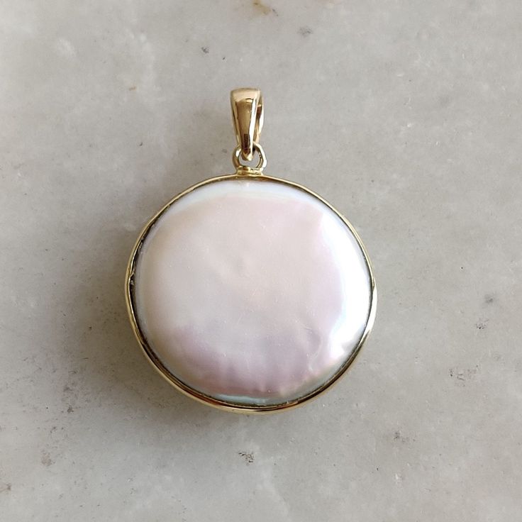 ITEM DESCRIPTION: >> The Pendant is made from Solid 14K Yellow Gold. Gemstone used is absolutely natural and ethically sourced. >> Natural Flat Cut mop  in round shape and bezel setting is studded on it with utmost precision.  >> This is a minimalist design and is absolutely hassle-free and everyday jewelry.  Gem:  Pearl  Gem size: 20mm Round Gem weight: 3.42  carats Gold purity: 14K (58.33% approx.) Gold weight: 0.60 grams  Gross weight: 4.02 grams The Gold purity is guaranteed and it comes with authentic 14K gold hallmark. Since this Pendant are handmade, It is Nickel/Lead FREE.  CUSTOMISATION: --> Earrings of the same design is also available on my Etsy Shop. --> You can choose your own gemstone. Kindly drop a message for more options. CUSTOMER SUPPORT: We are available 24/7 to respond Polished Mother Of Pearl Pendant Jewelry, Yellow Gold Jewelry With Mother Of Pearl, Round Shape, Yellow Gold Mother Of Pearl Round Jewelry, Yellow Gold Round Mother Of Pearl Jewelry, Round Mother Of Pearl Gemstone Jewelry, Round Pearl Pendant Jewelry From Mother Of Pearl, Yellow Gold Jewelry With Mother Of Pearl, Round Mother Of Pearl Pendant Jewelry, High Luster Round Necklaces As Gifts