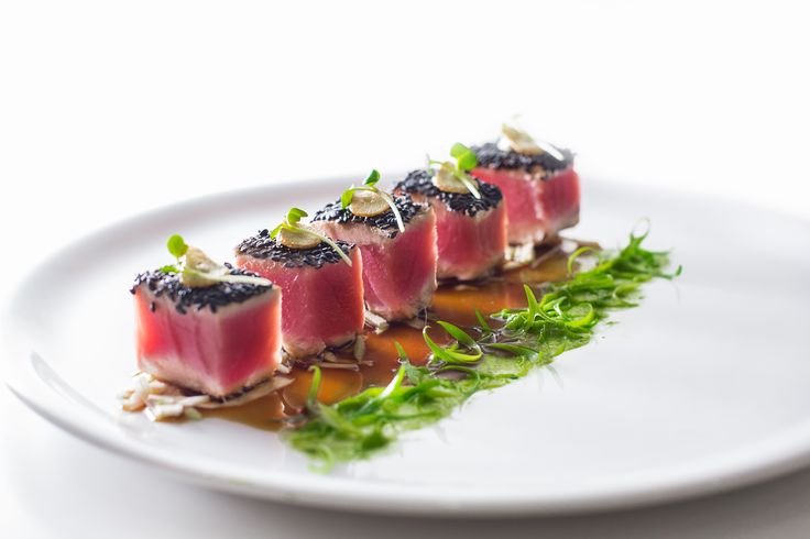 a white plate topped with small pieces of food on top of green leafy garnish