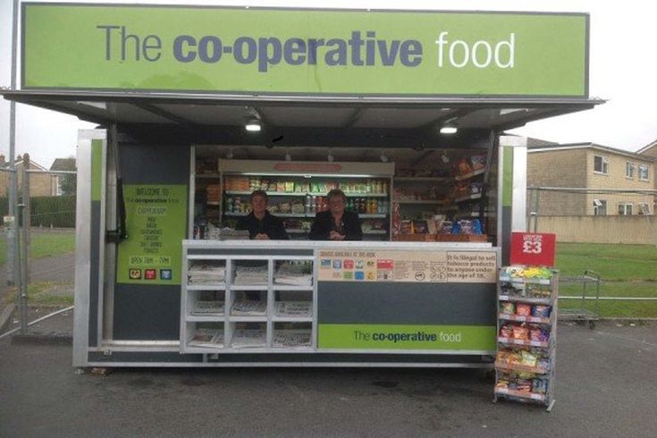 a food stand with two people standing in front of it and the sign above it says the co - operative food