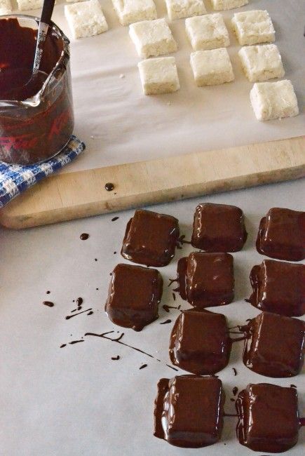 chocolate and marshmallows sit on a baking sheet next to a bowl of sauce