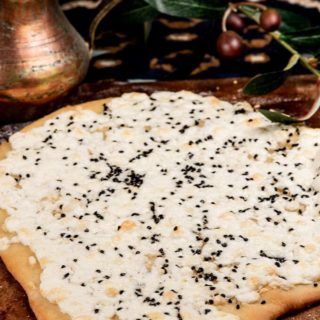 a pizza sitting on top of a cutting board covered in cheese and black pepper sprinkles