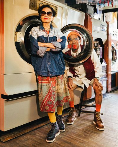 two people standing next to each other in front of a washing machine